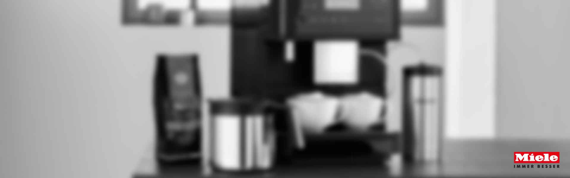 Miele Kaffeemaschine CM6 mit MilkPerfection System, zwei Gläser Cappuccino, Milchbehälter rechts, schwarzer Hintergrund.